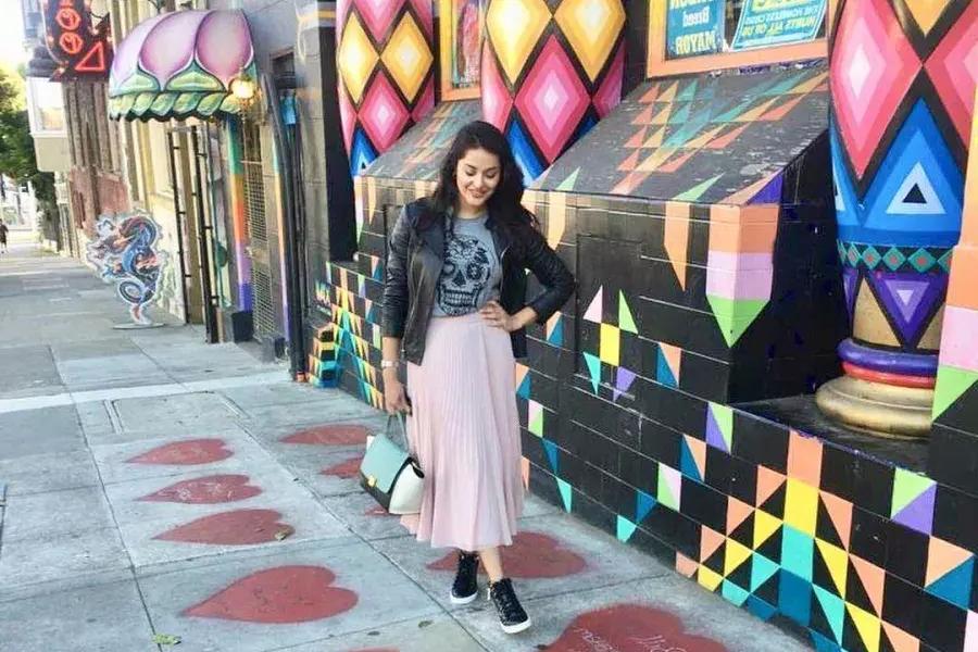 woman stands on A sidewalk painted with red hearts, colorful storefront in front of a, in San Francisco's Haight-Ashbury neighborhood.