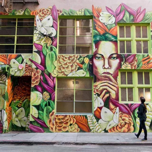 A woman looks up at a brightly colored mural on 的 side of an ornate building in San Francisco.